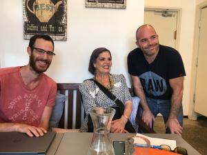 Three people sitting at a table with a clock on the wall behind them.
