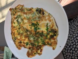 A white plate topped with an omelet covered in greens.