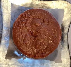 A chocolate cake sitting on top of wax paper.