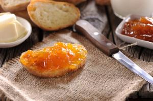 A piece of bread with orange jam on it.