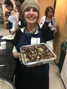 A woman holding a pan of food in front of her face.
