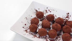A white plate topped with chocolate covered truffles.