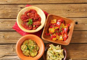 A wooden table with four bowls of food.
