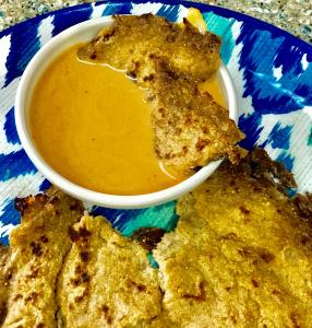 A bowl of sauce and some food on a plate.