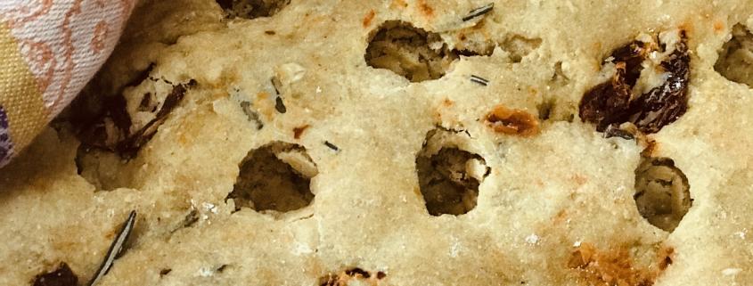 Dimpled rosemary olive focaccia on kitchen towel