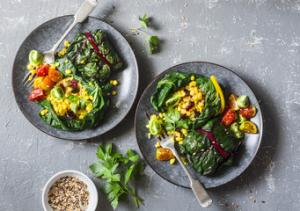 Two plates of food on a table with a bowl of salad.