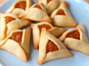 A plate of hamantaschen cookies with pepperoni.