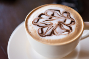 A cup of coffee with swirly design on it.