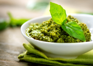 A bowl of green beans with pesto in it.
