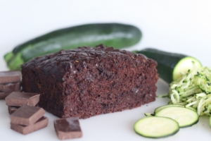 A piece of chocolate cake with cucumber slices on the side.