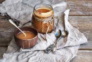 Jar of caramel sauce with spoons on linen