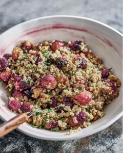 A bowl of food with grapes and nuts.
