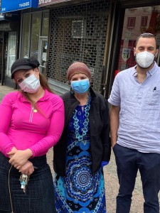 Three people wearing masks standing on a street.