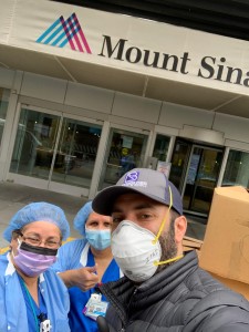 A man wearing surgical masks and gloves standing next to two other people.