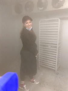 A woman in black robe standing next to a rack.