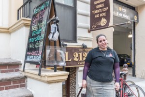 A woman standing outside of a restaurant holding two poles.