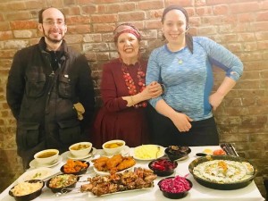 Three people standing in front of a table full of food.