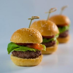 A row of mini hamburgers with lettuce and tomato.