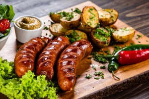 A wooden cutting board topped with meat and potatoes.