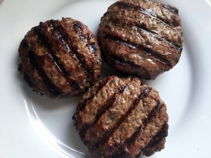 Three hamburger patties are sitting on a plate.