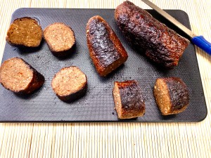 A black cutting board with some meat and potatoes on it