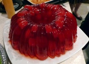 A red jelly cake on top of a white plate.