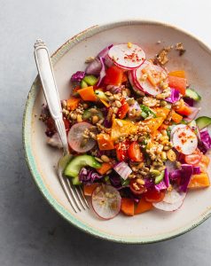 A bowl of salad with vegetables and dressing.
