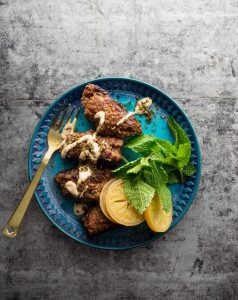 A blue plate with some meat and vegetables on it