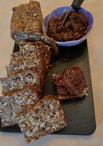 A loaf of bread and bowl of food on a table.