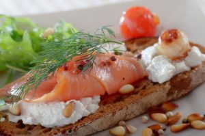 A piece of bread with salmon and cream on it.