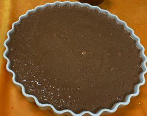 A pie crust with chocolate filling on top of it.