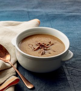 A bowl of soup with a spoon and napkin.