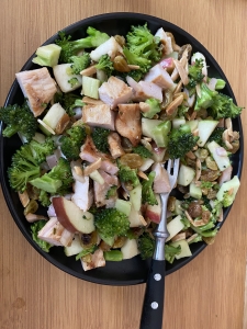 A plate of food with broccoli, apples and meat.