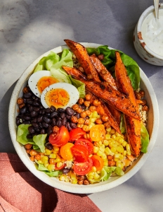 A bowl of food with eggs, corn and beans.