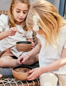 Two girls are eating food from bowls.